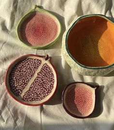 three pieces of fruit sitting on top of a white tablecloth next to a bowl