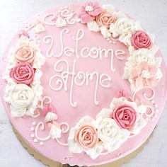 a pink cake decorated with flowers and the words welcome home written in white frosting