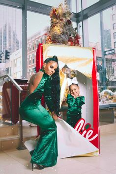 a woman in green dress standing next to a giant coca cola sign with a child on it