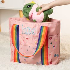 a person is holding a stuffed animal in a pink tote bag on the floor