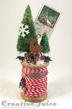 a spool of red and white twine next to some christmas trees on a table