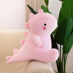 a pink stuffed animal sitting on top of a couch next to a potted plant