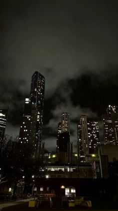 the city skyline is lit up at night with clouds in the sky and buildings on either side