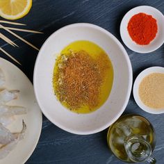 an assortment of spices and seasonings in bowls next to plates with food on them