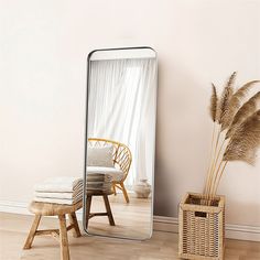 a large mirror sitting on top of a wooden floor next to a chair and potted plant