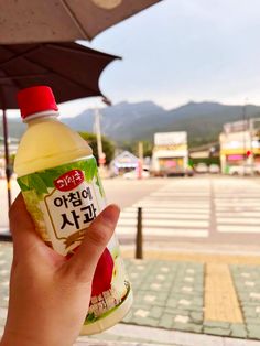 a person holding up a bottle of yogurt in front of an open umbrella