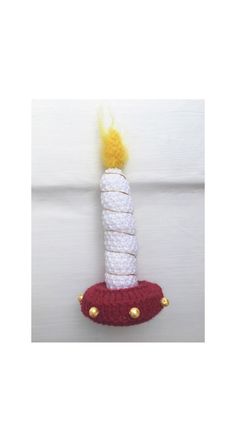 a knitted rocket ship ornament with a white and yellow candle on top