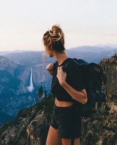 a woman standing on top of a mountain with a backpack