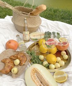 an assortment of fruits and pastries on a picnic table with bread, lemons, watermelon, grapefruit