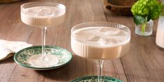 two glasses filled with liquid sitting on top of a wooden table