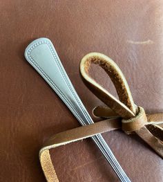 a pair of scissors sitting on top of a piece of leather with a ribbon tied around it