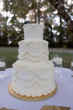 a wedding cake sitting on top of a table next to glasses and utensils