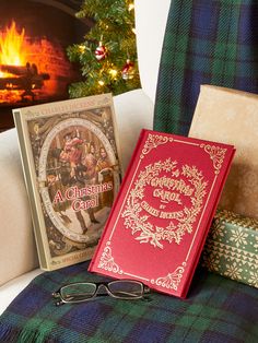 two books sitting on top of a couch next to a christmas card and book bag