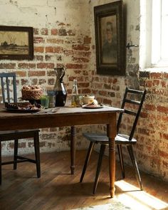 an old brick wall and wooden table in a room with two chairs next to it