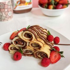 a white plate topped with chocolate covered pastry and strawberries next to a bowl of strawberries