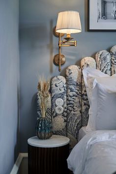 a bed room with a neatly made bed next to a lamp and pictures on the wall