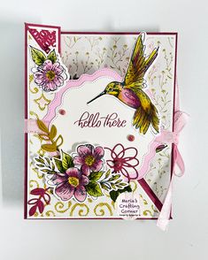 a close up of a card with a hummingbird on it and flowers in the background