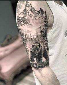 a man's arm with a bear and mountains tattoo on the left upper arm