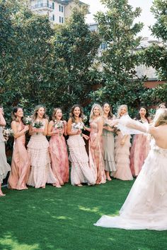 a group of women standing around each other in dresses