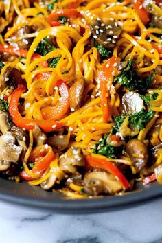 a skillet filled with noodles, mushrooms and broccoli on top of a marble counter