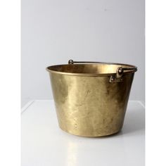 an old brass bucket is sitting on a white surface