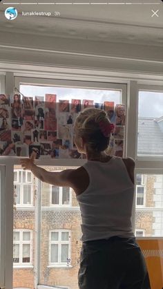 a woman standing in front of a window with pictures on it