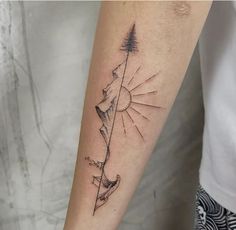 a person with a tattoo on their arm that has a mountain and trees in it