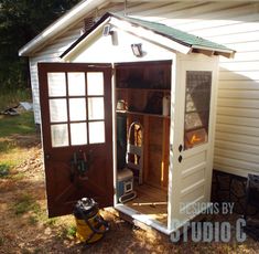 an outhouse with the door open and tools in it's storage compartment outside