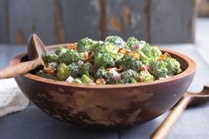 a wooden bowl filled with broccoli on top of a table