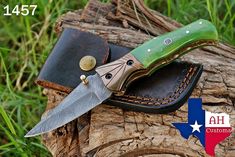 a knife is sitting on top of a leather case with a green blade in it