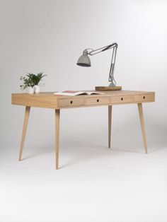 a wooden desk with a lamp on top of it next to a potted plant