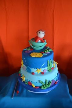 a three tiered cake decorated with an image of a boy in a boat on top