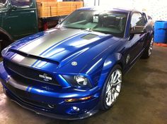 a blue mustang is parked in a garage