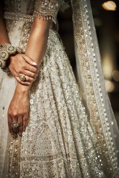 a close up of a person wearing a wedding dress and holding the hand of another person's arm