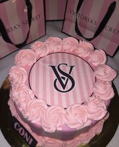 a cake with pink frosting and roses on the top is surrounded by shopping bags