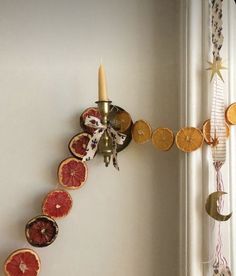 a candle is lit on a wall with fruit slices hanging from it's sides