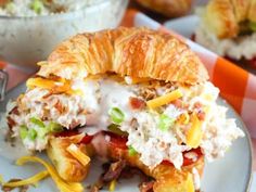 a croissant sandwich with bacon, cheese and other toppings on a plate