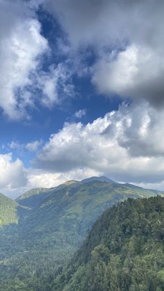 the mountains are covered in trees and clouds