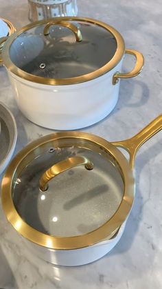 two white and gold pans sitting on top of a counter