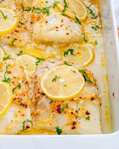 baked fish with lemons and herbs in a white casserole dish