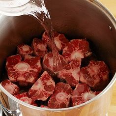 raw meat is being poured into a pot