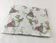 the fabric is white and has cartoon characters on it, including two girls with spoons