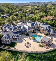 an aerial view of a large home with a pool in the foreground and mountains in the background