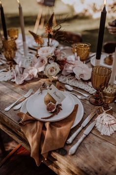 a wooden table topped with plates and candles