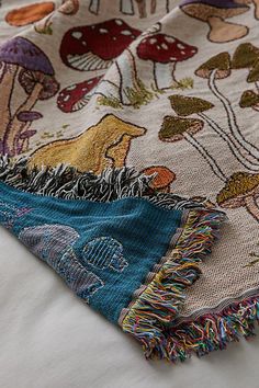 a close up of a blanket on a bed with animals and mushrooms in the background