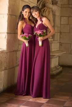 two beautiful young women standing next to each other in long purple dresses holding bouquets