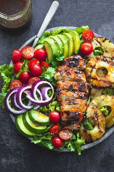 grilled chicken, avocado, tomatoes and onions on a plate next to a glass of beer