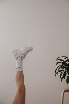 a person's foot with white socks and a plant in the corner behind them