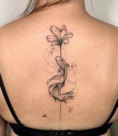 the back of a woman's shoulder with a fish and flower tattoo on it