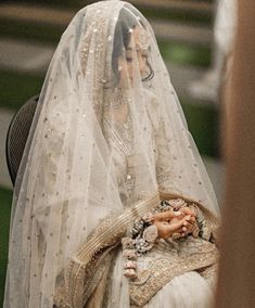 a woman wearing a veil and holding a doll in her hand while standing next to another person